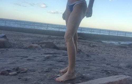 a picture of a woman showing her toned abs outside the beach