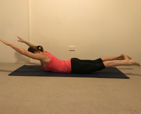 2B a woman doing a superman pose on a yoga mat