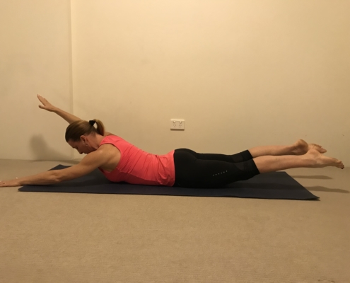 2C a woman doing a superman pose on a yoga mat