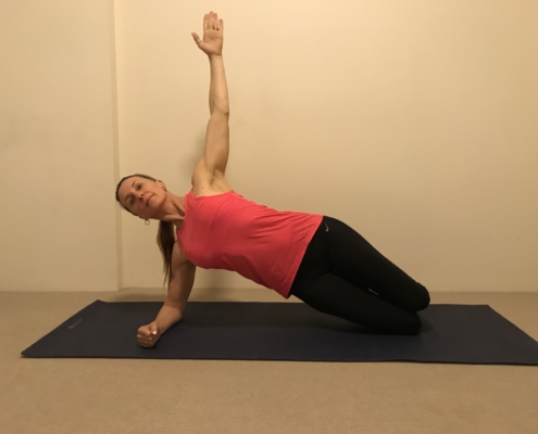 3A a woman doing a side plank on a yoga mat