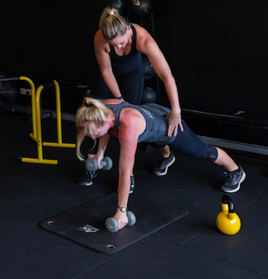 Shot 5 a woman doing her strength training inside a gym with a personal trainer